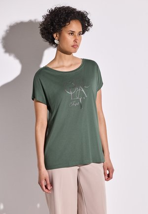 Groene t-shirt met korte mouwen, gemaakt van zachte stof, met een zilveren grafisch tekstontwerp. Gepaard met taupe wijde broek.