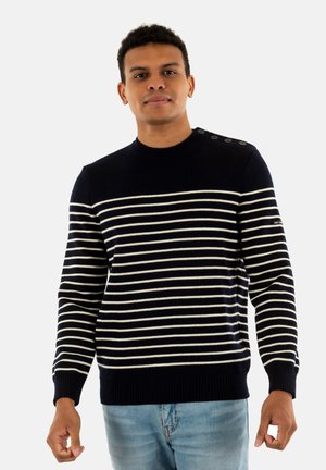 Maglione a righe blu navy con righe orizzontali bianche, dotato di dettagli con bottoni sulla spalla e polsini e orlo a costine.