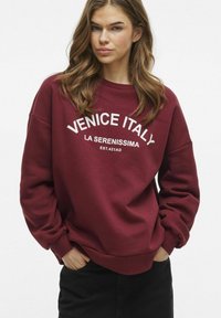 Felpa bordeaux con testo bianco "VENEZIA ITALIA LA SERENISSIMA EST. 421AD." Presenta una vestibilità comoda e polsini a costine.