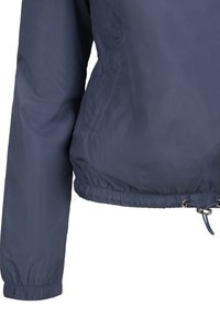Manche et taille de veste bleu marine avec poignets élastiques et cordon ajustable à l'ourlet, présenté sur fond blanc.