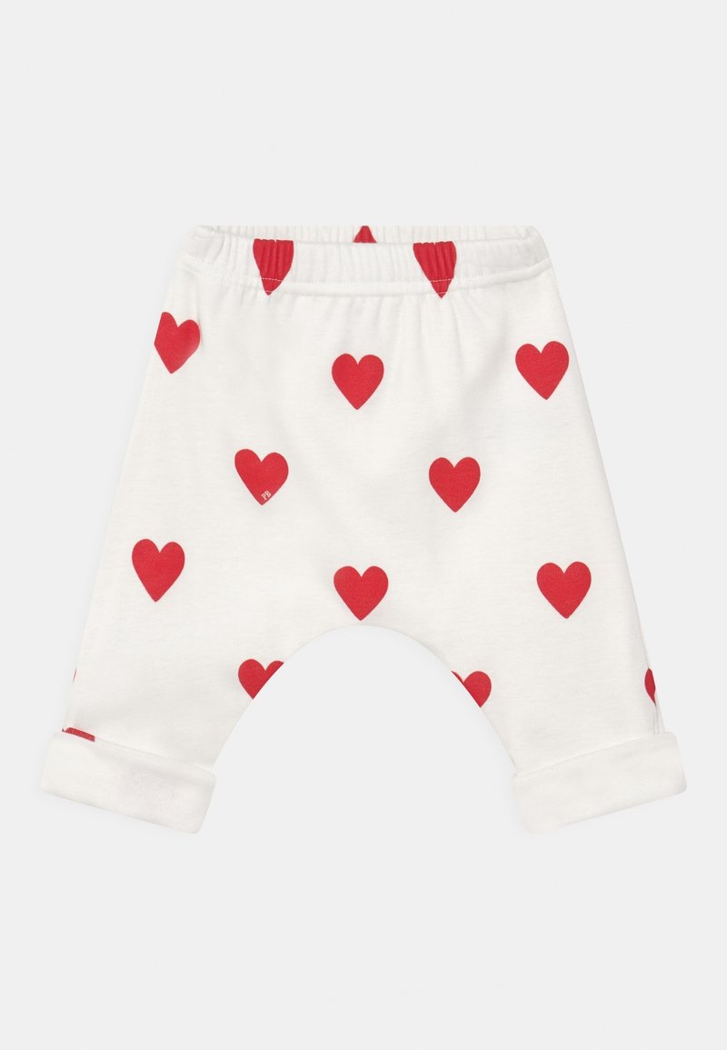 Pantalons bébé blancs avec des motifs de cœurs rouges, dotés d'un ourlet retroussé et d'une taille élastique pour le confort. Tissu en coton doux.