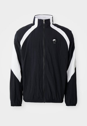 Schwarz Windbreaker-Jacke mit weißen diagonalen Akzenten, hohem Kragen, Reißverschluss vorne und Logo auf der linken Brust. Leichtes, strukturiertes Material.