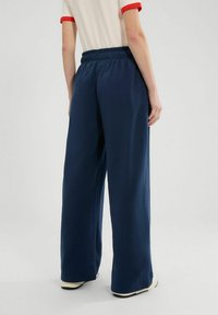 Marine brede pijpen met een zachte textuur, elastische tailleband en twee zijzakken, gecombineerd met contrasterende rode afwerking op het shirt.