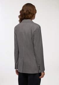 Szary marynarka w prążki z dopasowanym krojem, z klapami i mankietami na trzy guziki. Gładki materiał o lekkim połysku.