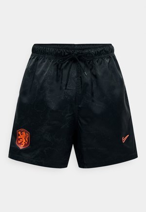Mustad sportpüksid elastse vöö ja nööriga, vasakul säärel oranži lõvikreestiga ning paremal säärel oranži Nike logoga.