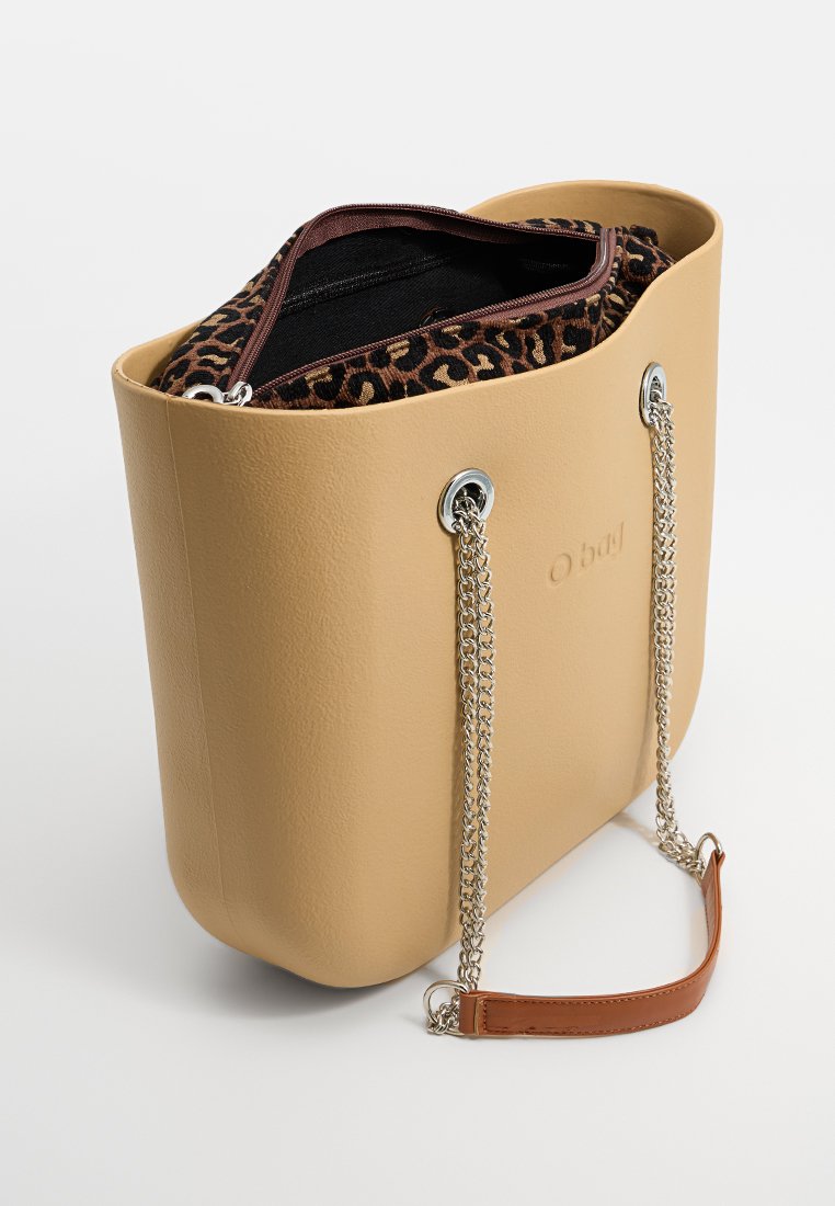 Beżowa torebka typu tote z imitacji skóry o usztywnionym kształcie, z metalowymi srebrnymi łańcuszkami, wewnętrzna podszewka w cętkowany wzór, oraz zamek błyskawiczny.