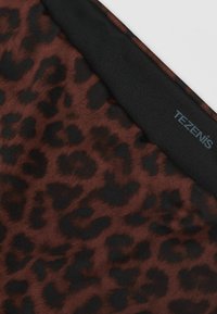 Tkanina s leopardím vzorem v hnědé a černé barvě, s hladkým povrchem a černým pasem. Viditelná značka "TEZENIS".