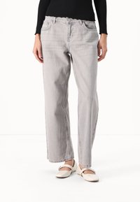 Ljust grå högmidjade jeans med avslappnad passform, subtil blekning och en mjuk denimtextur. Har en traditionell knapp- och dragkedjefly.