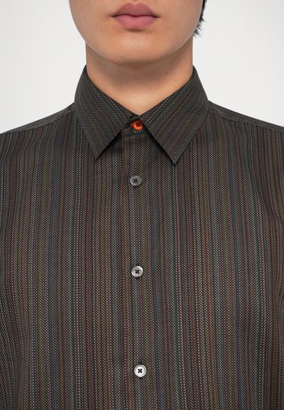 Camisa de manga corta, con cuello, de tejido oscuro con rayas verticales multicolores. Presenta un botón rojo y dos botones grises en la parte delantera.