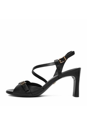 Sandalo con tacco alto in pelle nera con cinturini incrociati, punta aperta e dettagli con fibbie dorate sui cinturini alla caviglia e sul davanti.