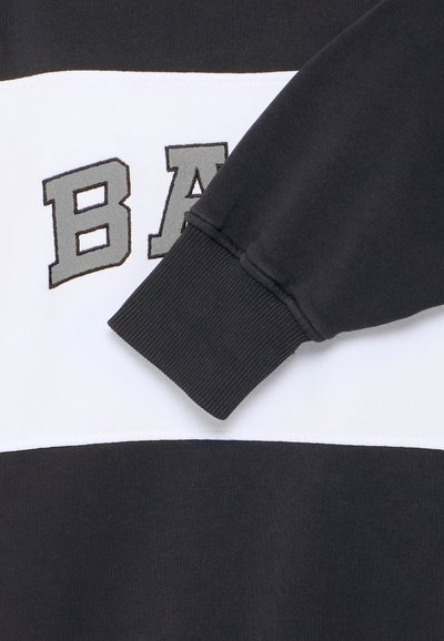 Sudadera en blanco y negro con un audaz logo "BA" en gris. El material es algodón, con puños de canalé y textura suave.