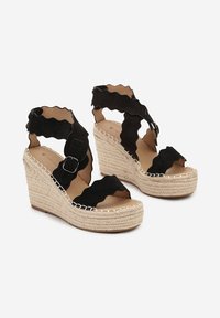 Des sandales à talons compensés en daim noir présentent des brides festonnées, des boucles à la cheville et une plateforme en jute enveloppée avec des détails de couture contrastants.
