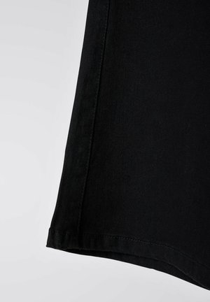 Black denim fabric, mid-length with a straight cut. Features a clean hem and subtle texture, emphasizing durability and simplicity.