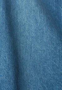 Gros plan sur un tissu en denim bleu montrant une texture détaillée et un motif de tissage avec un léger ombrage.