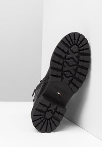 Czarny skórzany but z solidną gumową podeszwą, teksturowanym bieżnikiem i bocznym zamkiem błyskawicznym. Posiada logo na podeszwie i elegancki design.