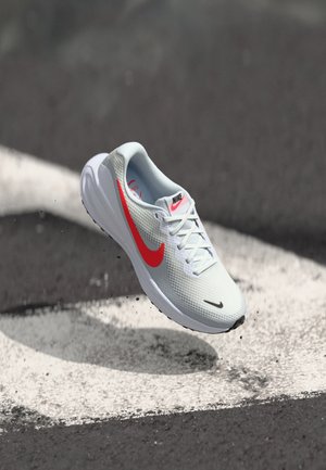 Nike tekaške čevlje v svetlo sivi barvi z teksturiranim mrežastim zgornjim delom in drznim rdečim logotipom Swoosh. Ima bele vezalke in oblazinjeno podplat.