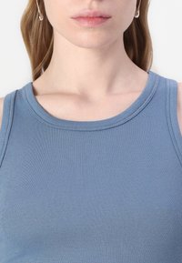 Svetlomodrá rebrovaná top s okrúhlym výstrihom. Hladká textúra, bezrukávový dizajn, s priliehavým strihom.