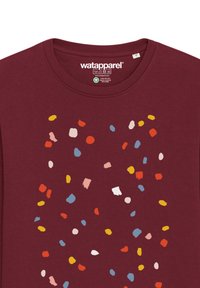 T-shirt à manches longues bordeaux avec un motif dispersé de taches colorées en rouge, bleu, jaune et rose. Tissu en coton doux.