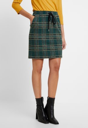 Vihreä ruudullinen hame, jossa on keltaisia ja mustia yksityiskohtia. Hameessa on elastinen vyötärö ja nauhakuja sekä sivutaskut. Mustat nilkkasaappaat.