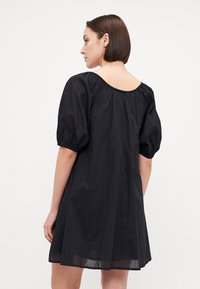 Μαύρο φόρεμα με φουσκωτά μανίκια, στρογγυλή λαιμόκοψη και λεπτομέρειες από gathered ύφασμα. Χαλαρή εφαρμογή με μήκος μέχρι το γόνατο και ελαφρύ ύφασμα.