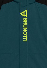 Tyrkysovo-čierna bunda s výrazným žltým logom "BRUNOTTI", hladká textúra a zapínanie na zips s vysokým golierom.