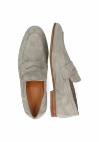 Grijze suede instappers met een moccasin-stijl ontwerp, voorzien van een decoratieve band en een bruine leren zool. Overal een gladde textuur.
