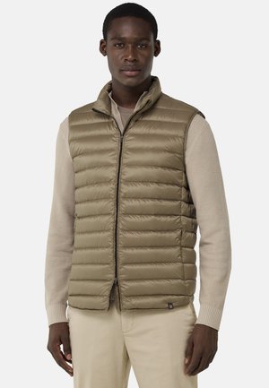 Gilet matelassé en vert olive, avec un col montant, une fermeture éclair à l'avant et des coutures horizontales. Porté par-dessus un pull beige texturé.