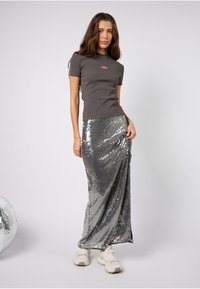Szara dopasowana koszulka z krótkim rękawem i różowym logo zestawiona ze srebrną, cekinową spódnicą maxi o błyszczącej, teksturowanej powierzchni.
