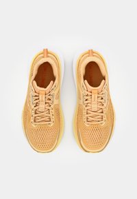 Baskets de course orange clair avec une tige en mesh respirant, des lacets plats et une semelle intermédiaire jaune. Comprend un talon renforcé et un détail de logo.