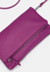 Lila Leder Crossbody-Tasche mit silbernem Reißverschlussfach und abnehmbarem Tragegurt, geprägt mit dem Markennamen "Liebeskind Berlin" auf der Vorderseite.