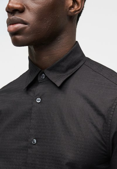 Camisa preta de abotoar com padrão texturizado subtil, gola clássica e botões azuis, feita de um tecido suave.