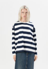 Navy and white striped long-sleeve top, round neckline, relaxed fit, paired with a denim skirt. The fabric is soft with a smooth texture.