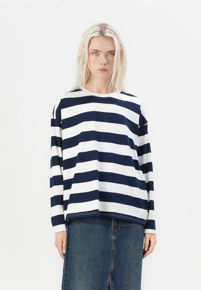 Navy and white striped long-sleeve top, round neckline, relaxed fit, paired with a denim skirt. The fabric is soft with a smooth texture.