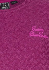 Fuchsia stickad tröja med ett texturerat mönster, utformad med rund hals och broderad "Indian BlueJeans" logotyp i rosa.