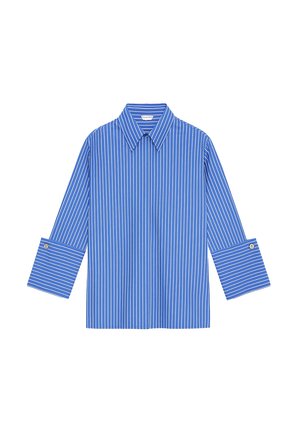Chemise bleu clair à boutons avec rayures blanches verticales, larges poignets et col pointu, présentée à plat sur un fond blanc.