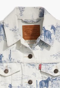 Bílá džínová bunda s potiskem modré západní krajiny, zapínáním na cvoky a štítkem. Textura je pevná, s detailní grafickou představou.