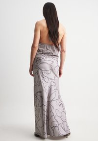 Long gray dress with floral outlines, featuring a low back and form-fitting design, made of smooth fabric. Floor-length with elegant draping.