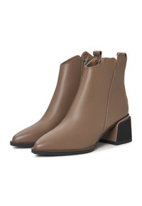 Botas de tobillo marrones hechas de cuero suave. Presentan una puntera en punta, cierre con cremallera y un tacón de bloque texturizado.