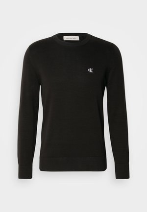 Suéter negro de punto con escote redondo, puños y dobladillo acanalados, que presenta un pequeño logo blanco de CK en el lado izquierdo del pecho. Textura suave.