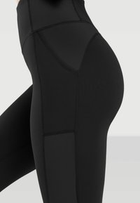 Black high-waisted leggings featuring a ribbed texture, smooth panels, and side pocket detail, designed for flexibility and comfort.