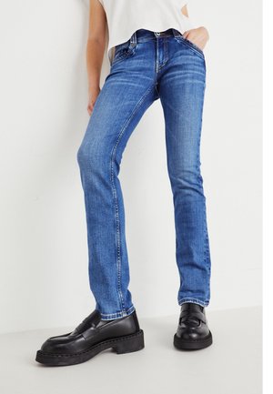 Blue denim jeans with a straight cut, five pockets, and subtle whiskering on the front. Paired with black loafers featuring a chunky sole.
