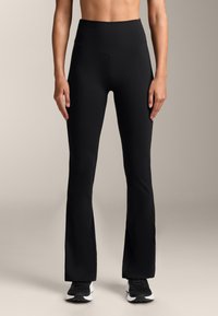 Pantaloni de yoga negri, evazați, dintr-un material elastic și neted, cu talie înaltă. Au detalii cusute la linia taliei și o siluetă ajustată.