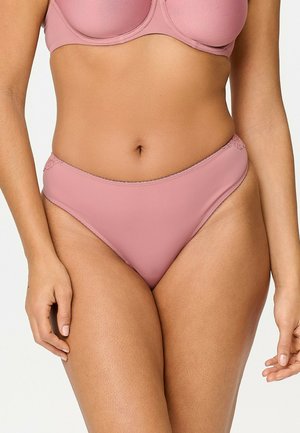 Donna che indossa reggiseno rosa chiaro abbinato e slip a vita alta con dettagli in pizzo sui fianchi, mostrata dalla metà del busto fino alle cosce superiori.