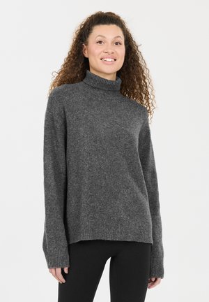 Dunkelgrauer, gestrickter Rollkragenpullover mit weiten Ärmeln und gerippten Bündchen, legerer Schnitt und weicher Textur. Kombiniert mit schwarzen Leggings.