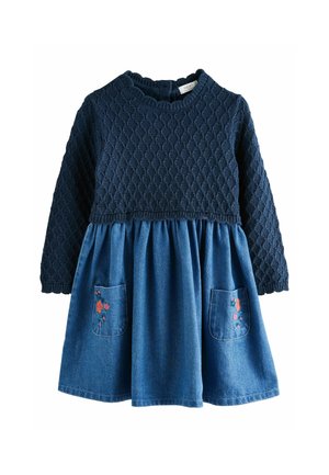 Corpetto lavorato a maglia blu navy con motivo strutturato, gonna in denim svasata e due tasche con ricami floreali in accenti rossi, rosa e blu.