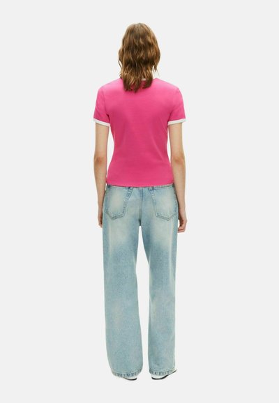 Aangemeten roze T-shirt met korte mouwen met witte boorden, gecombineerd met lichtblauwe hoge taille wijde jeans, die een casual achteraanzicht toont.