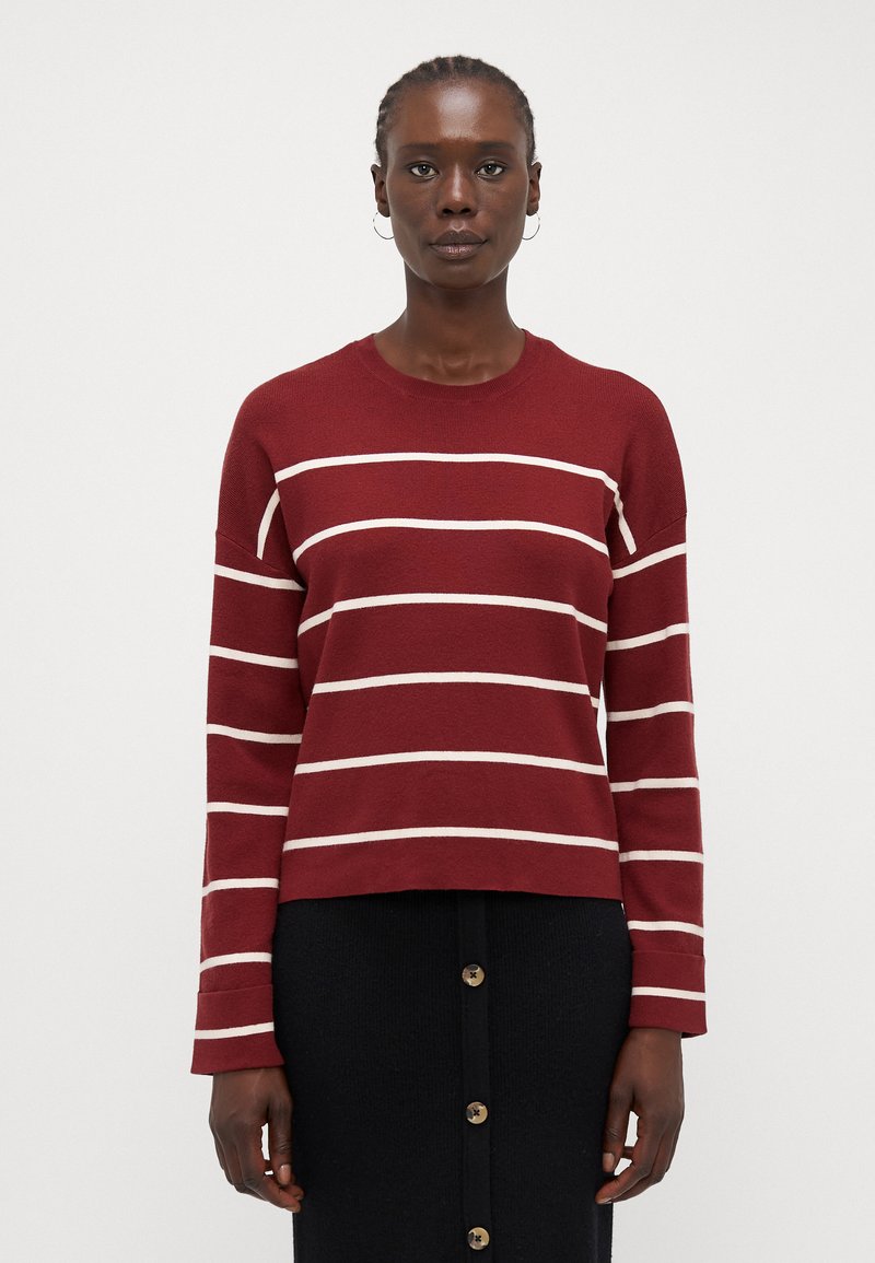 Maglione a righe bordeaux con linee orizzontali bianche, realizzato in tessuto strutturato. Presenta un collo a giro e maniche lunghe, con un design leggermente accorciato.