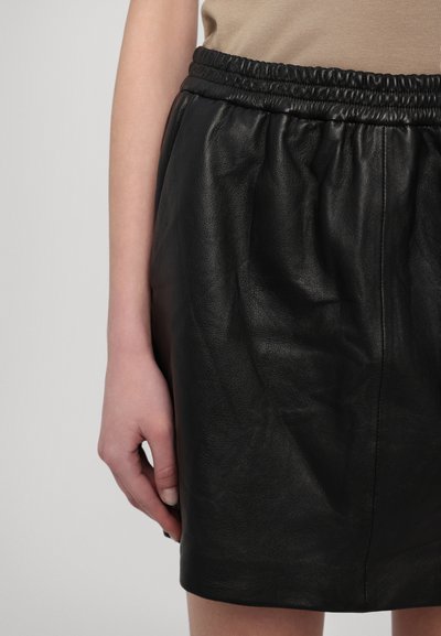 Black leather skirt with an elastic waistband. The material is smooth with a soft sheen, featuring subtle folds and a fitted design.