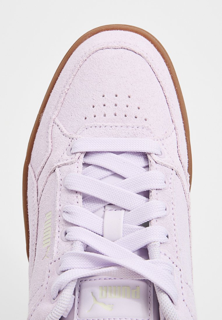 Baskets en daim violet clair avec perforations, lacets blancs et semelle en caoutchouc beige. Présente un logo doré sur le côté.