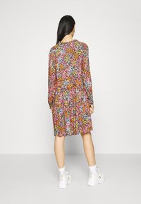Bloemen jurk met lange mouwen, met een kleurrijk patroon in roze, oranje en blauw. Halflang met een geplooid taille en een ronde halslijn.